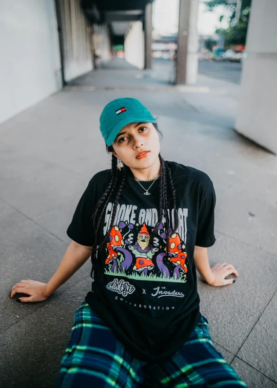 woman in t - shirt with dreadlocks sitting on the sidewalk