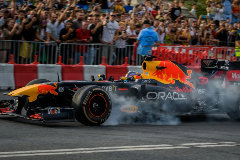 the red bull is coming through smoke while a crowd watches