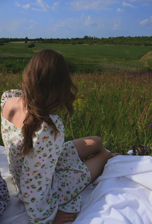 the girl sitting on the bed is looking off into the distance