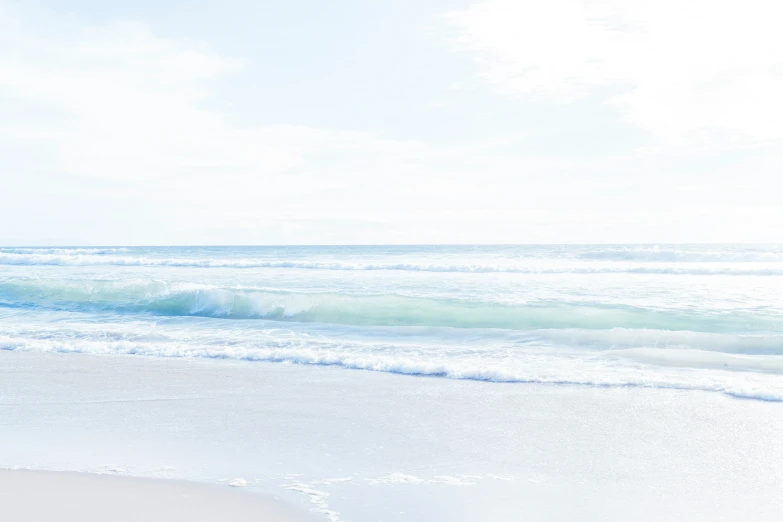 a beautiful sea foam beach with two surfers on the ocean