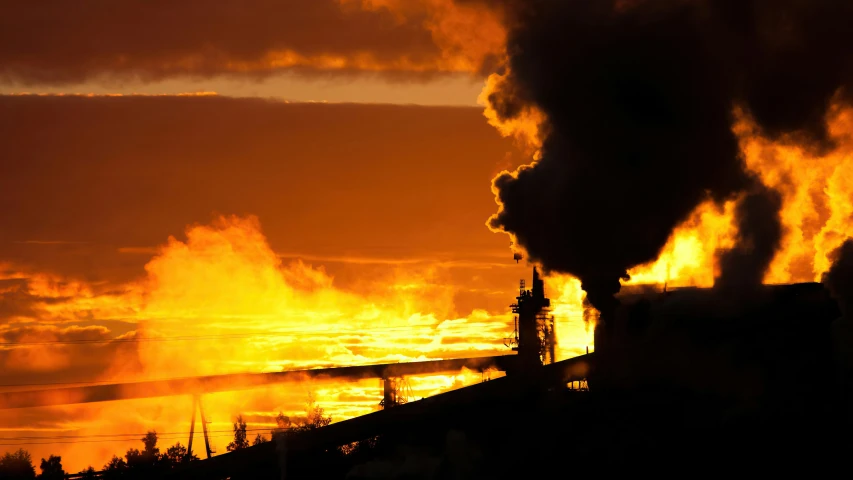 large orange smoke billowing out from the chimneys of factories