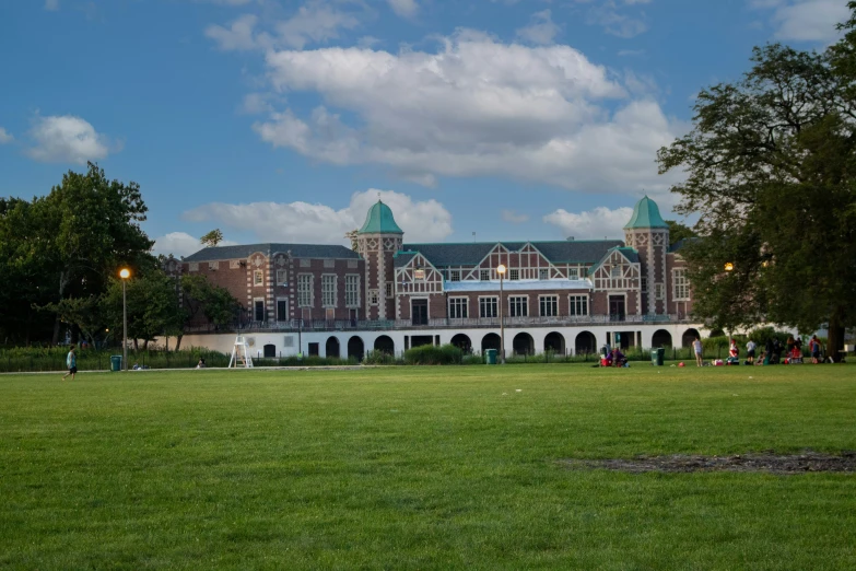 people outside in a field near a large building