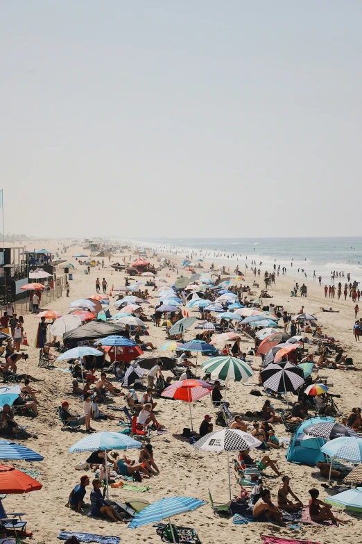 crowded beach area with people under umbrellas and onlookers