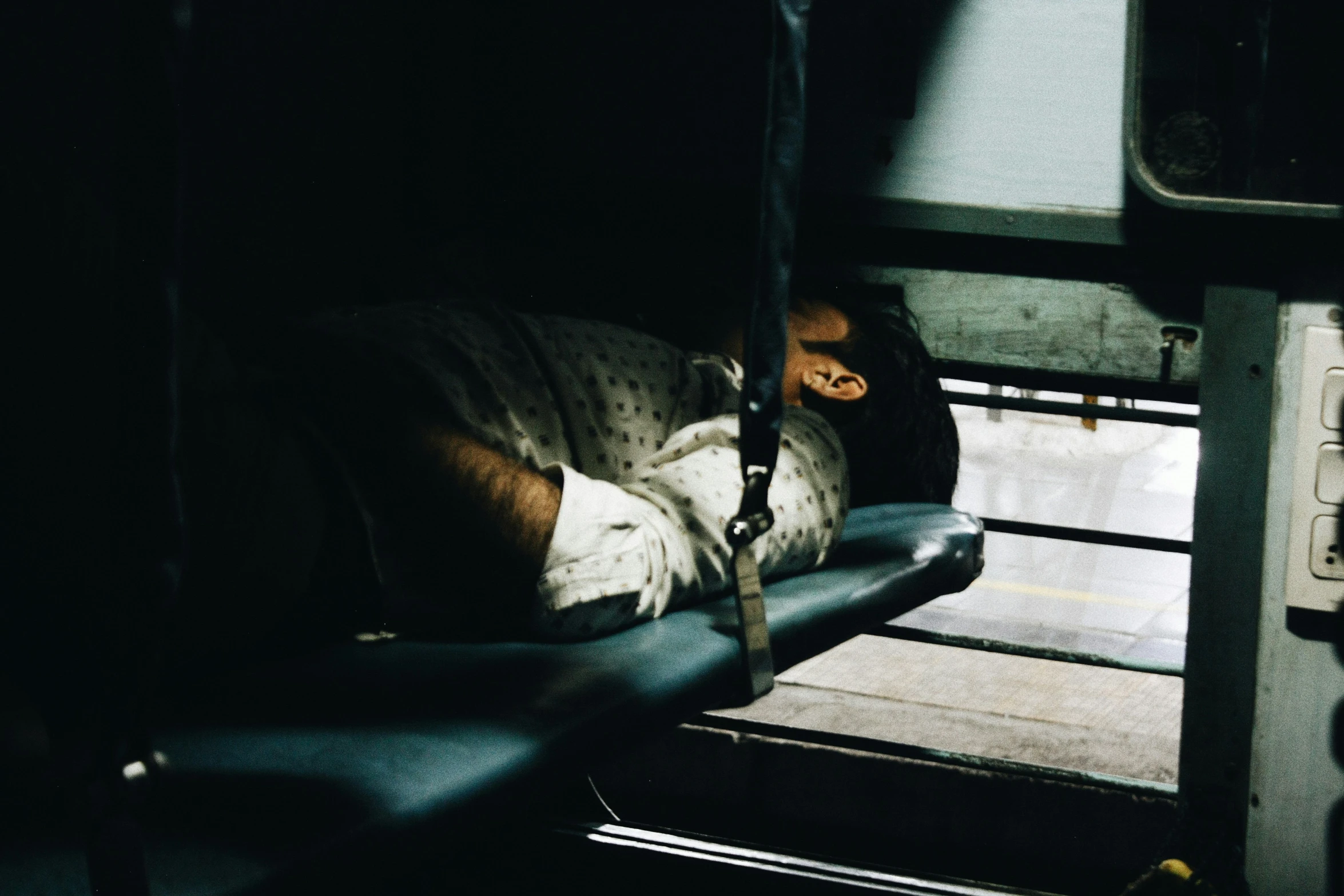 a person sleeping on top of a blue bench next to a doorway