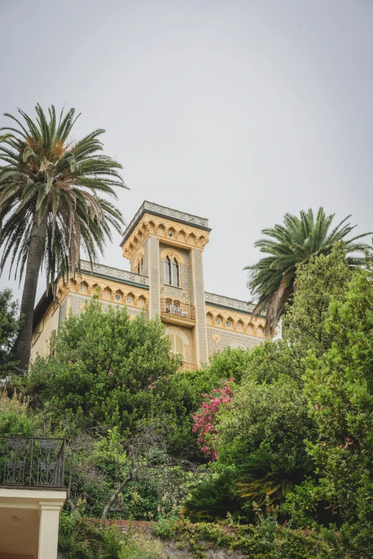 a castle with a clock tower near trees and bushes