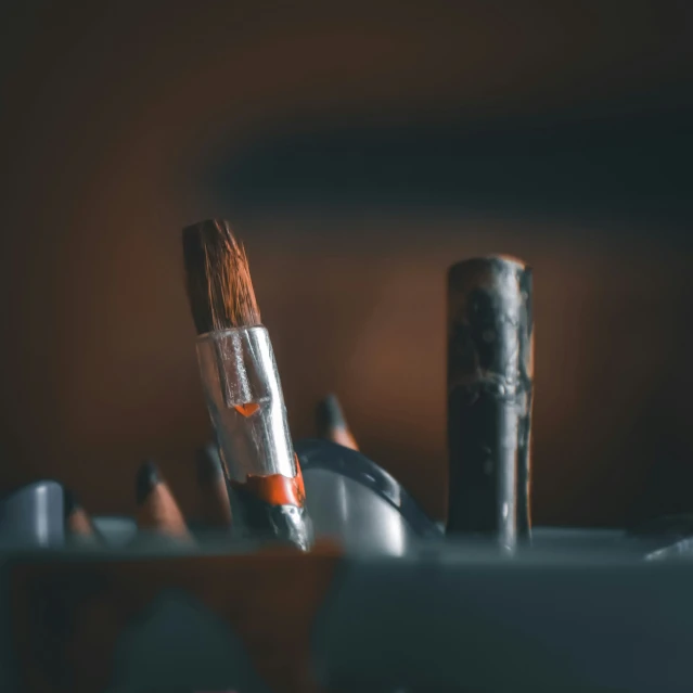 an orange pencil next to a large painting brush