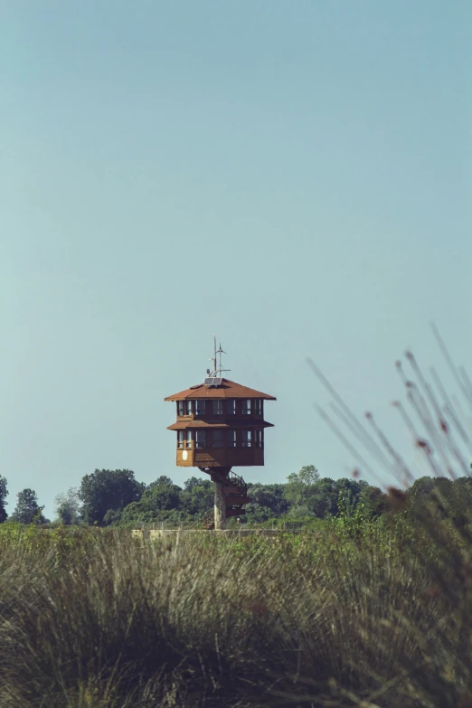 a tower in the grass with a building in the background