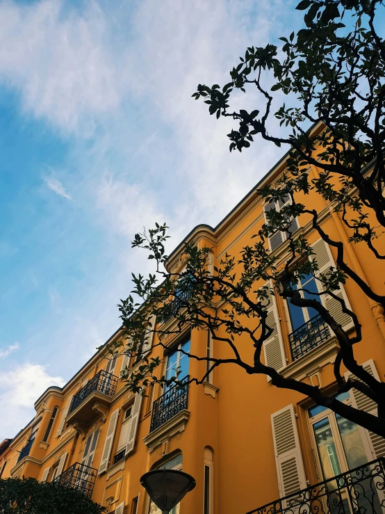 a large orange building with many windows next to a tree