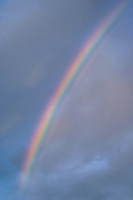 a rainbow appears to be above the clouds in a blue sky