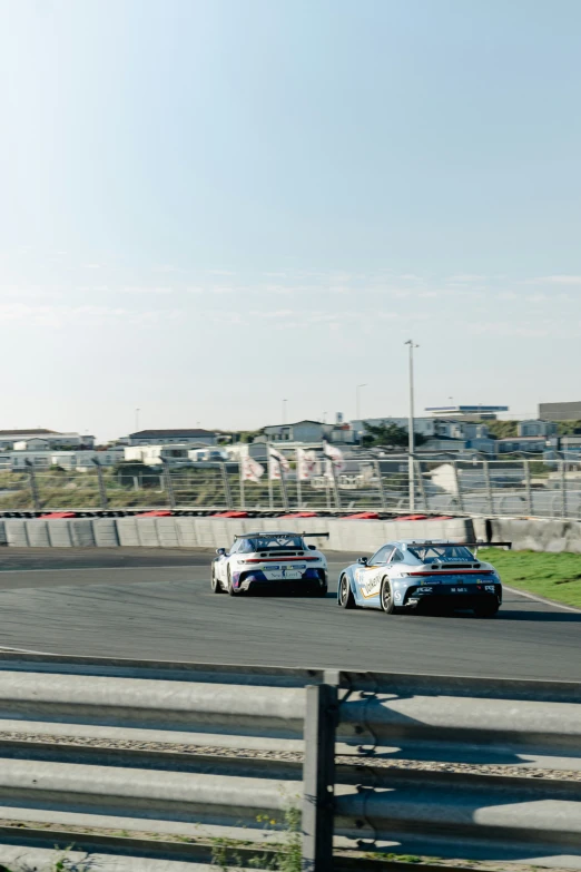 two cars driving around a track in the daytime