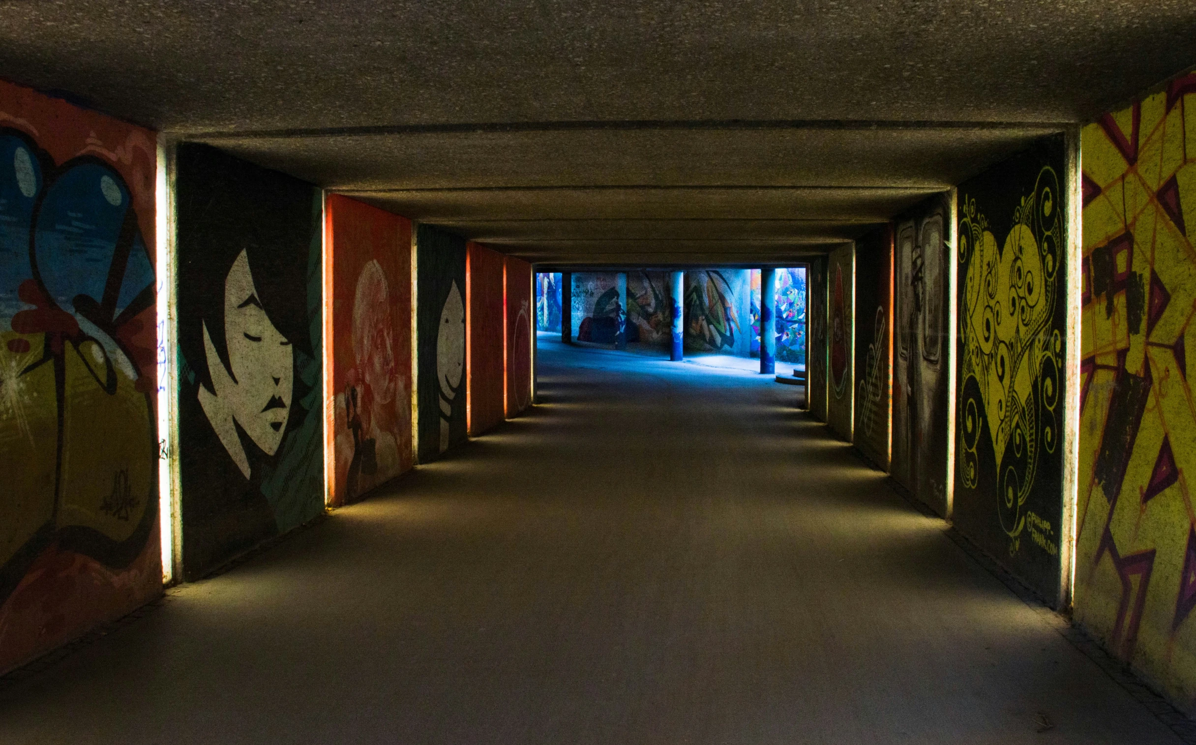 a long hallway with many doors covered in graffiti