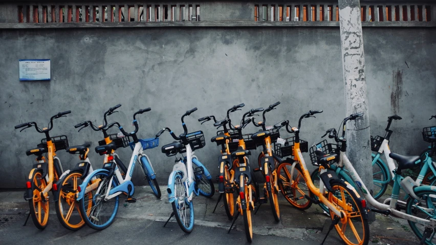 several bikes parked together in a row near a wall