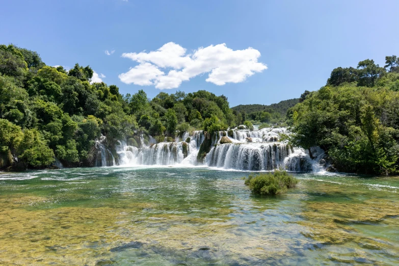 a river running through lush green forest with tall waterfall