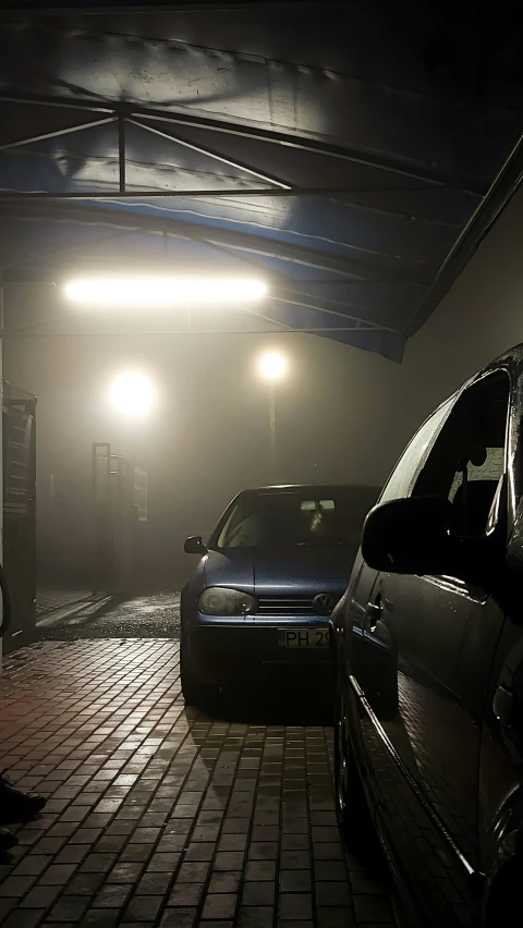 two cars in the fog sitting parked inside a building