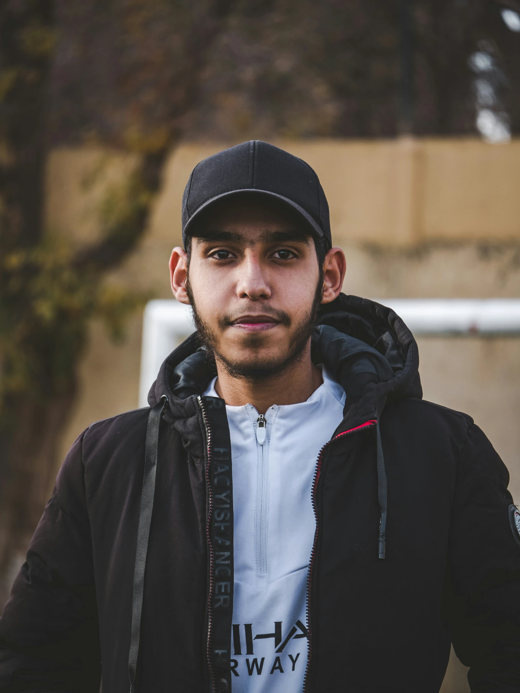 a man with a cap standing in front of a wall