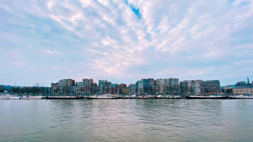 the clouds loom over an urban setting on the water