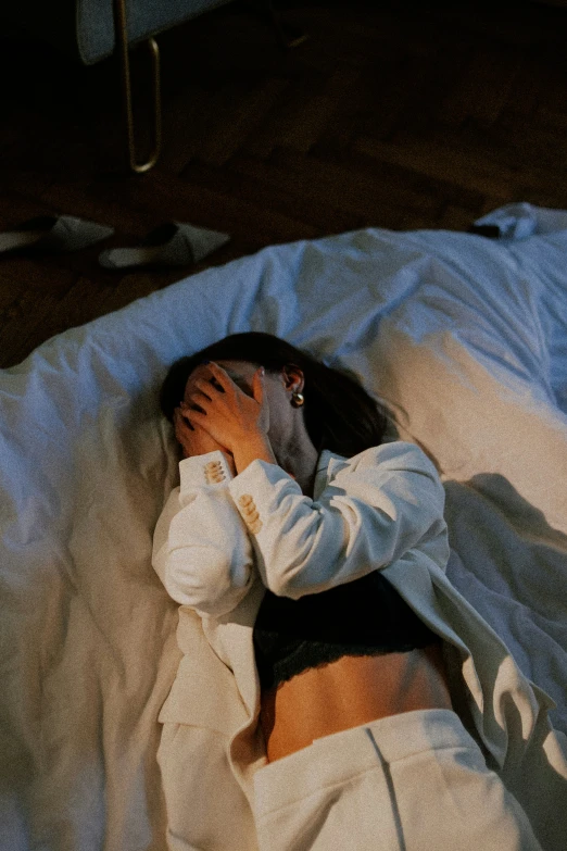 woman sleeping with hands on face on white sheet