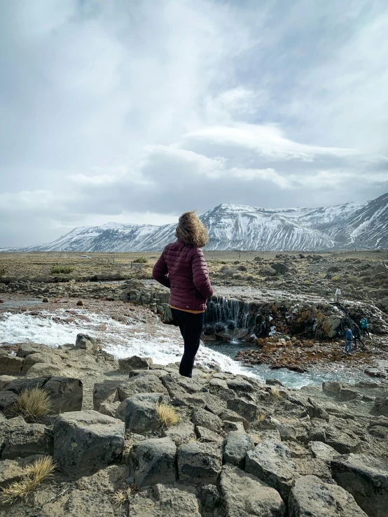 the woman is standing on top of the rocks