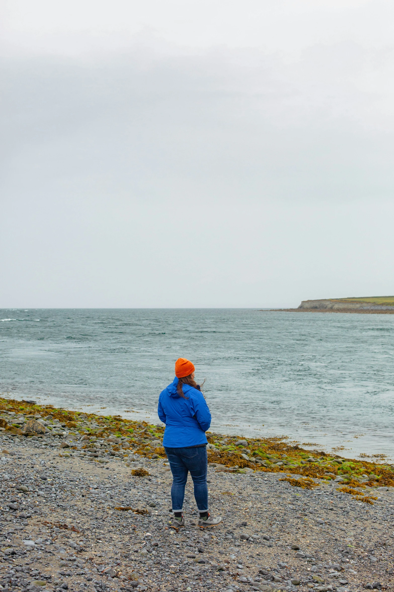 a man standing on a beach flying a kite