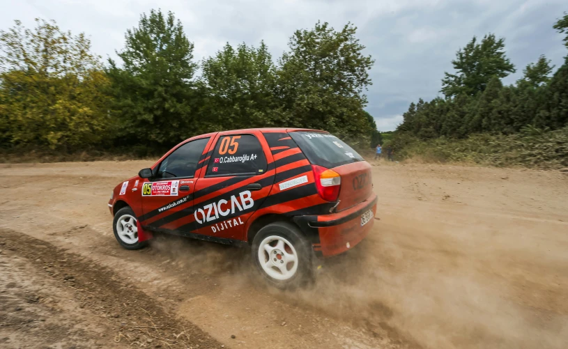 a red vehicle on dirt road near woods