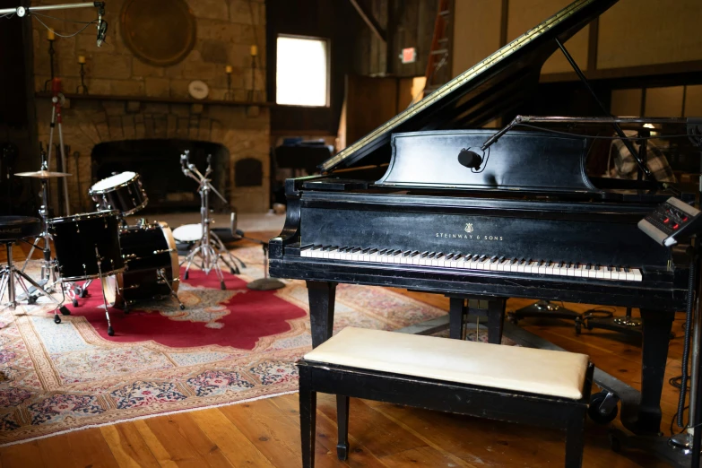 a living room with a piano, piano stool and drums