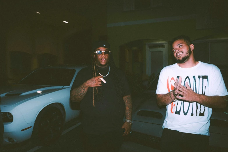 two men standing by a car at night talking