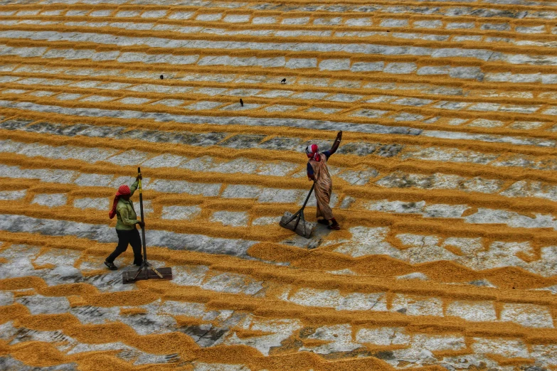 two men with brooms walking through yellow mud