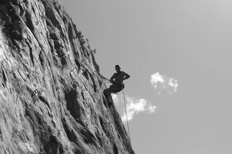 someone climbing down a steep rock face with a rope