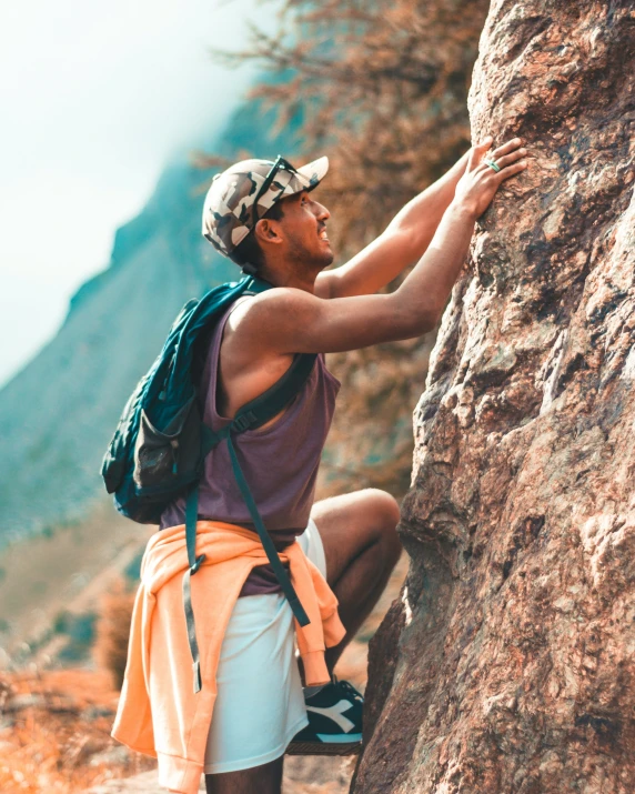 a man climbing a rock on the side of a mountain