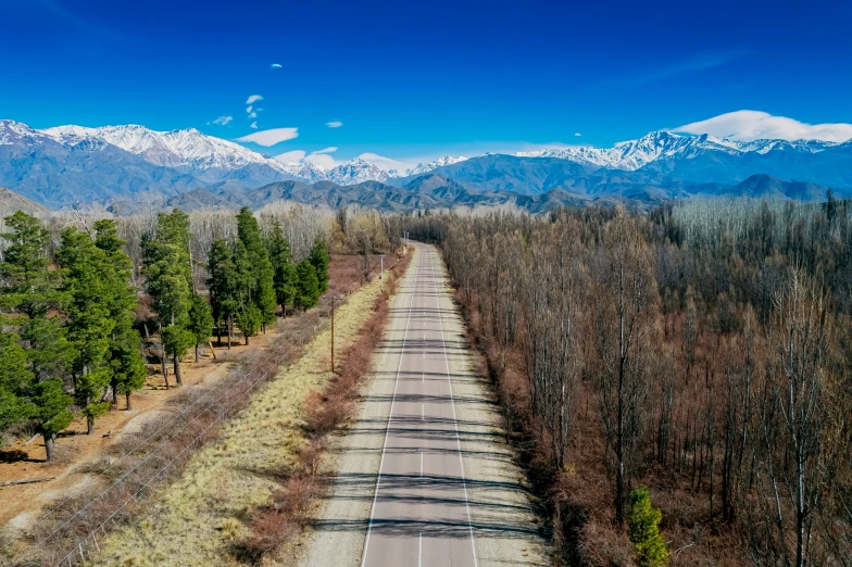 an aerial view of a road, with snow capped mountains in the distance