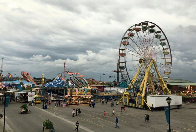 people gathered in an amut park next to an ferris wheel