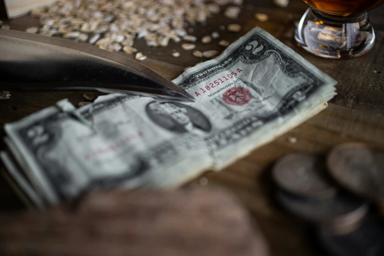 a paper dollar bill sitting on a wooden table next to some metal pieces