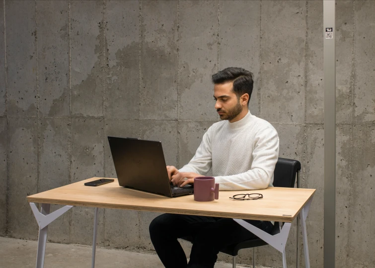 a man sits at a table working on his laptop