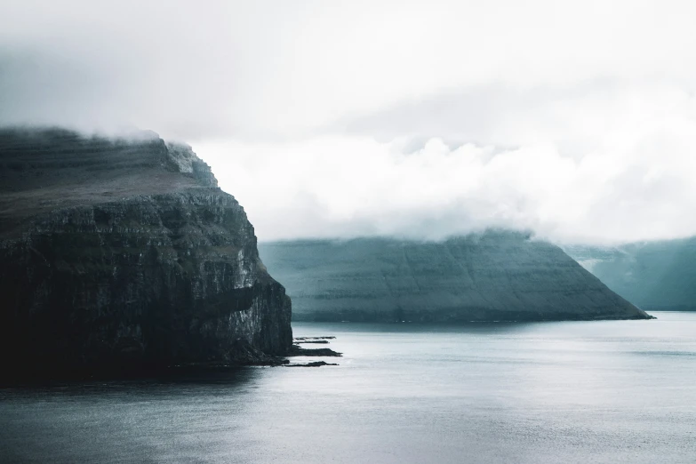 dark, rainy water near some rocks and a mountain