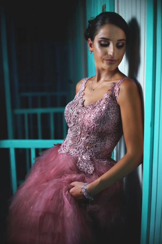 woman in pink dress standing against wall smiling