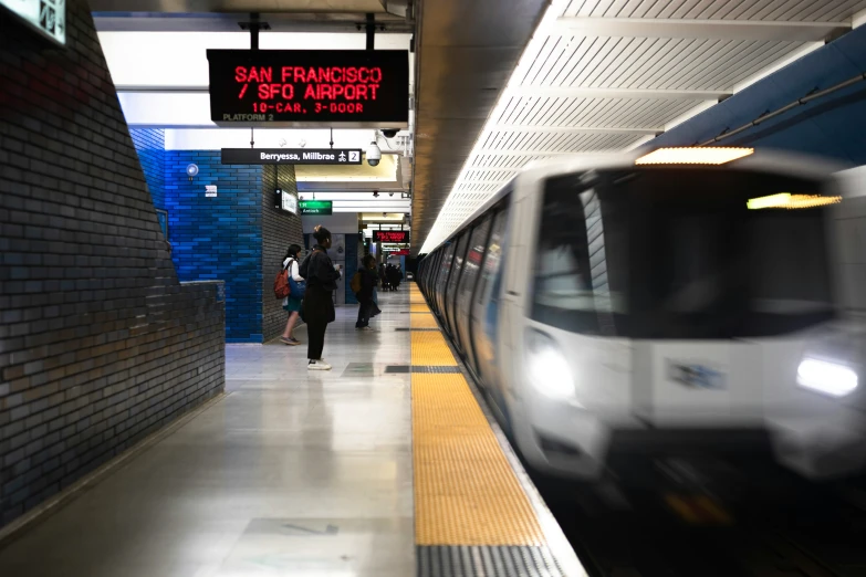 two people walking in front of a train at a station