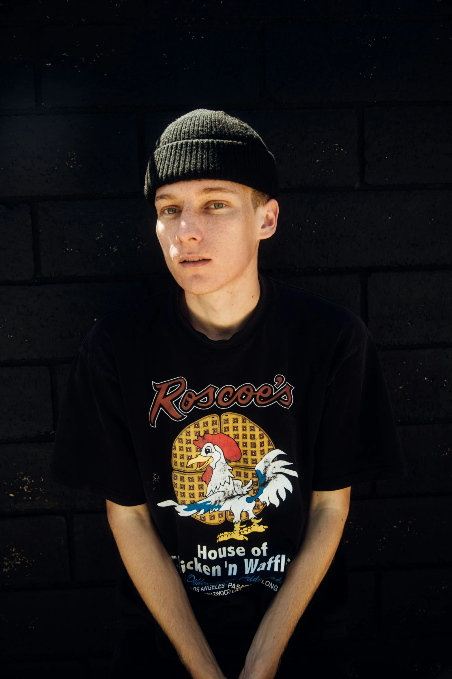  poses in a t - shirt against a brick wall