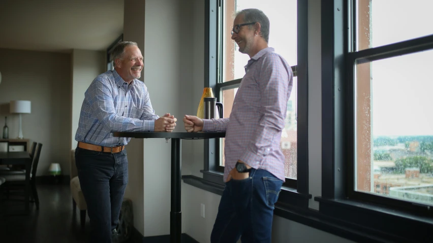 two men stand next to each other with drinks in their hands