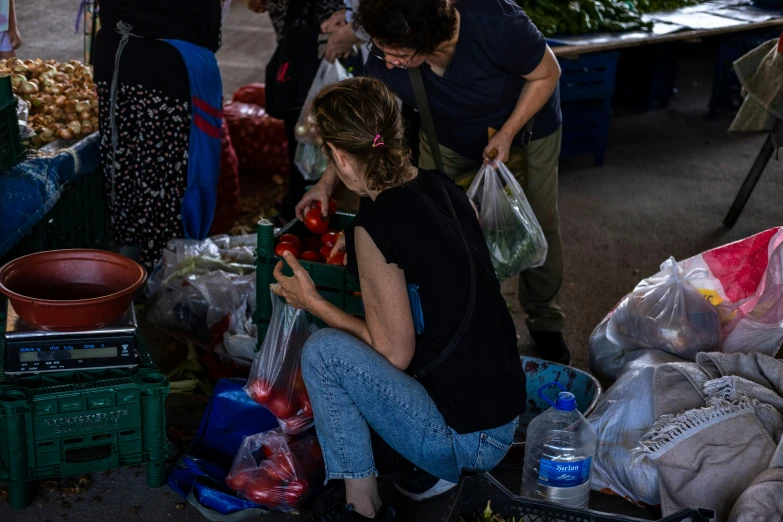 people stand with various produce in bags next to a table