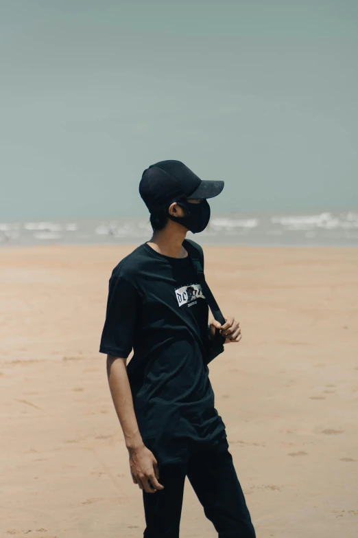 the man standing in front of a beach is wearing a hat and a shirt