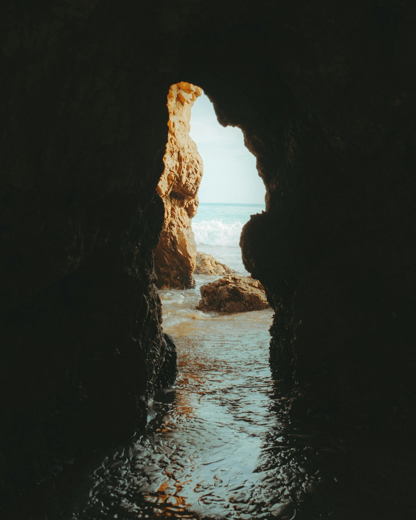 a view from inside of a rock cave on the beach