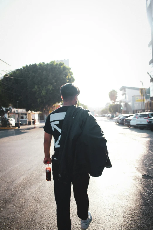 a man walks down the street with a backpack and drink