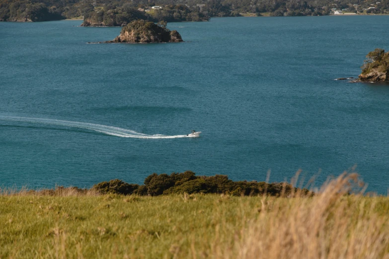 a boat sails on the water with island in the background