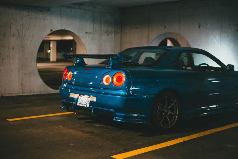 blue car parked in a parking garage next to a mirror