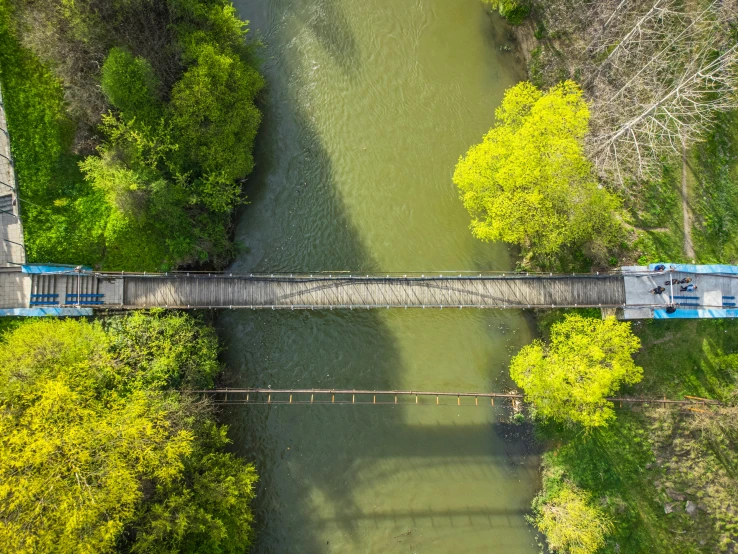 a bridge crossing a river surrounded by green trees