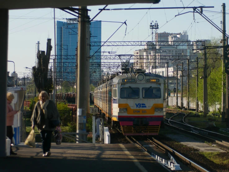 people walking along the track next to a commuter train on it