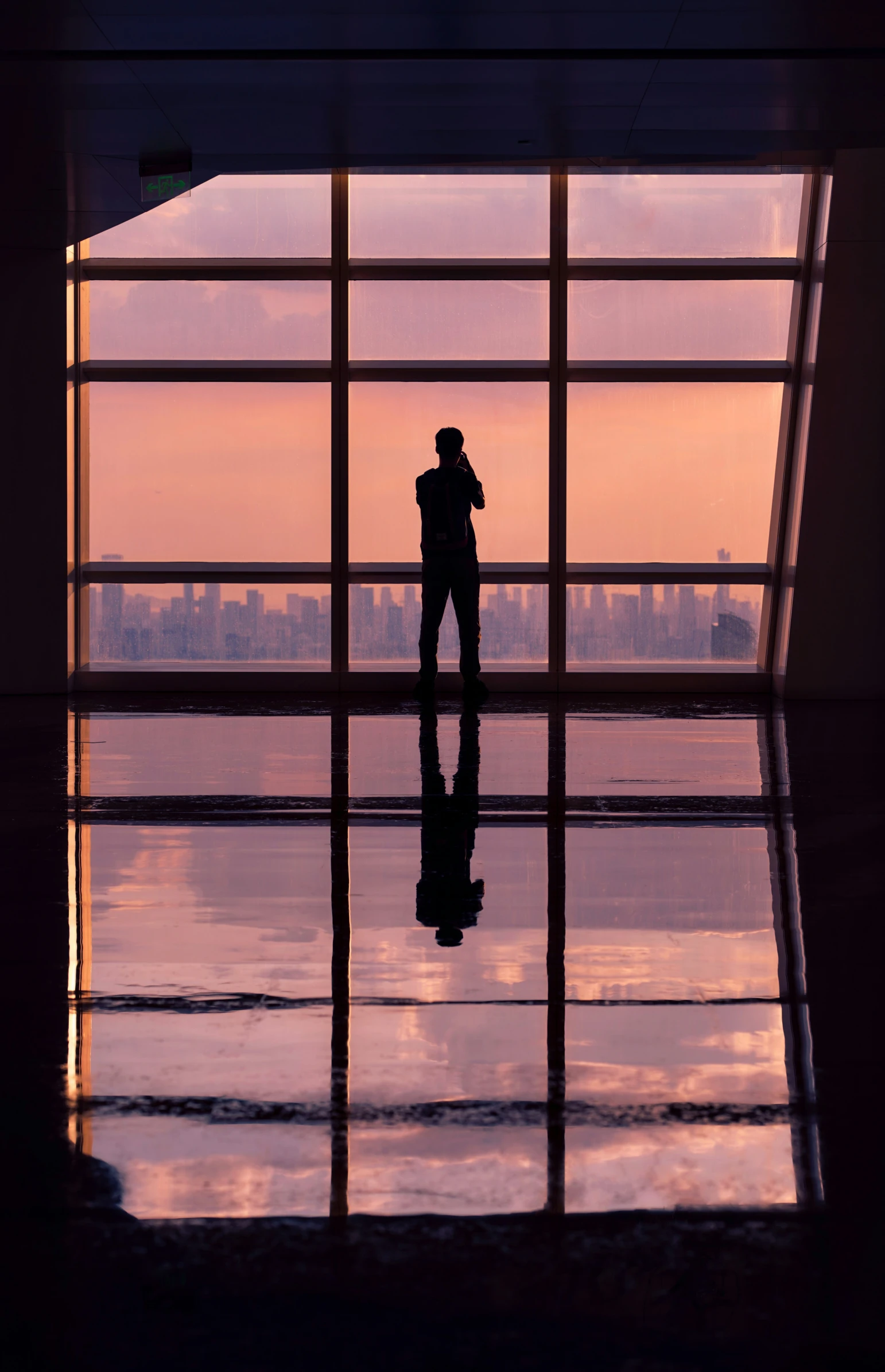 a person standing near a window that has a sunset view