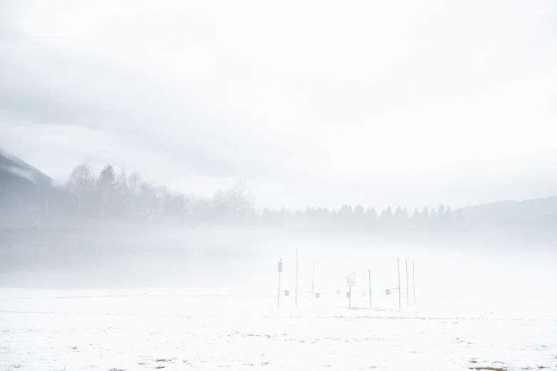 fog covering the top of a mountain and small wooden structures in the middle