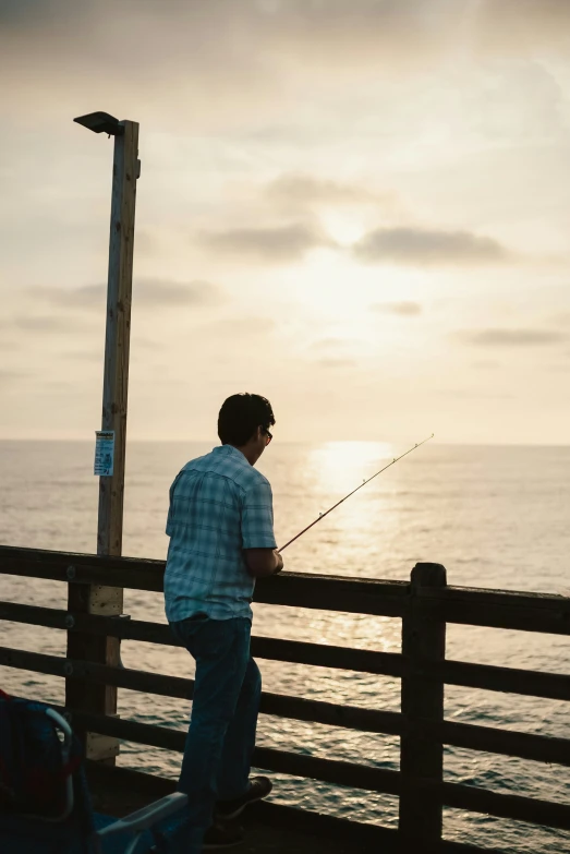 a man standing on a beach near the ocean fishing