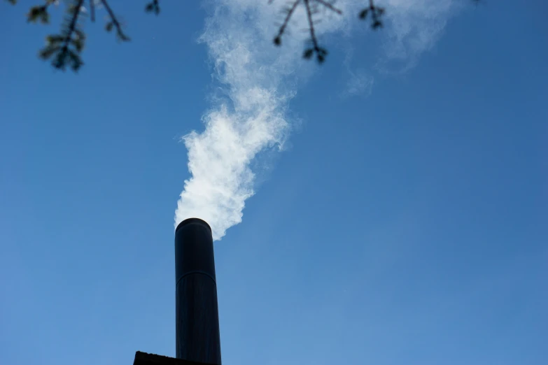 a smoke stack in the sky with the back lit